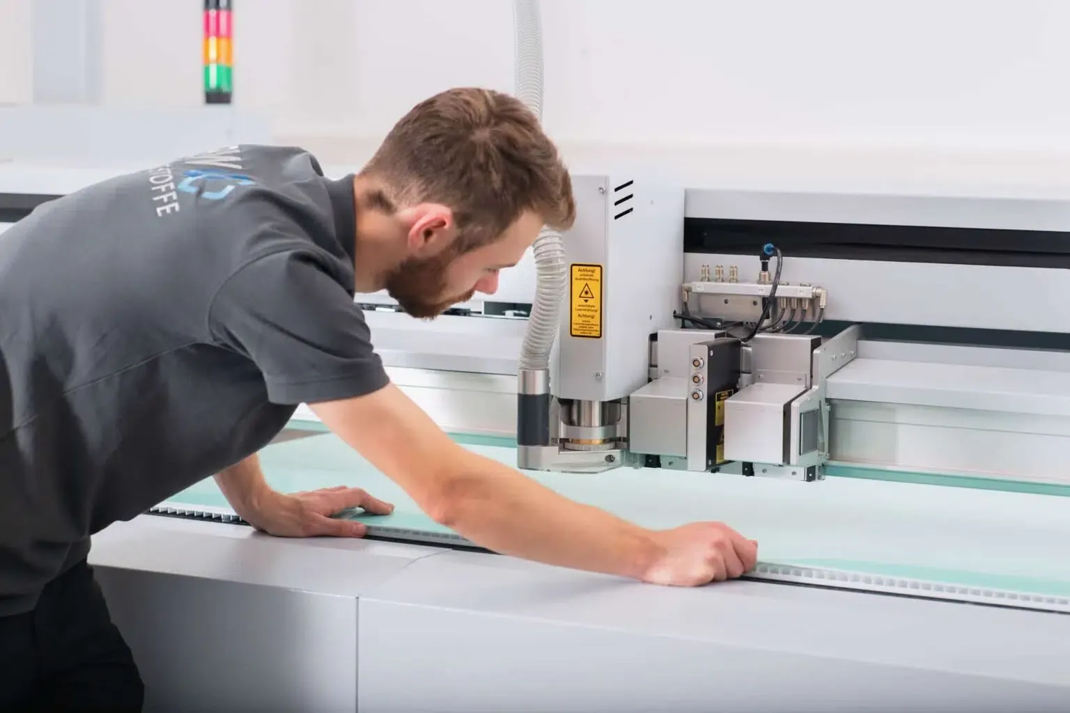 An employee aligns a plastic sheet on the production machine